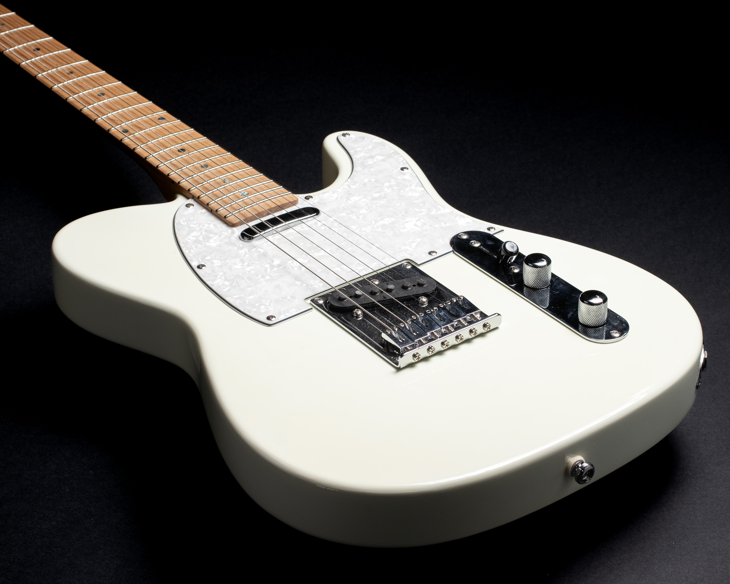 Cream electric guitar body against a dark studio background